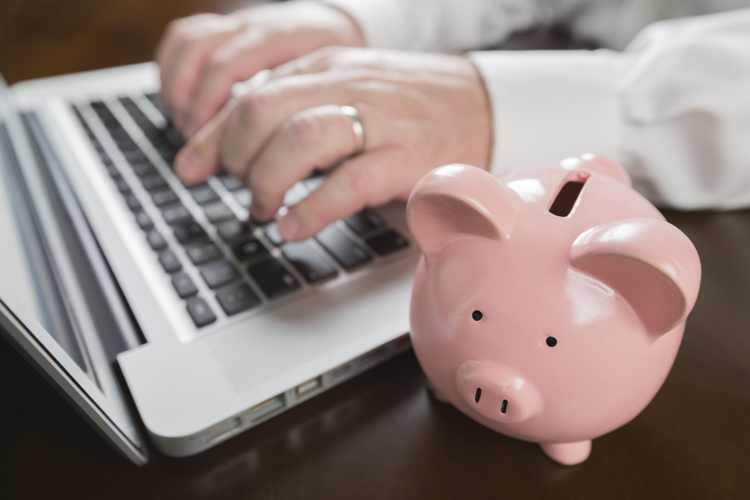 Piggy,Bank,Near,Male,Hands,Typing,On,Laptop,Computer.